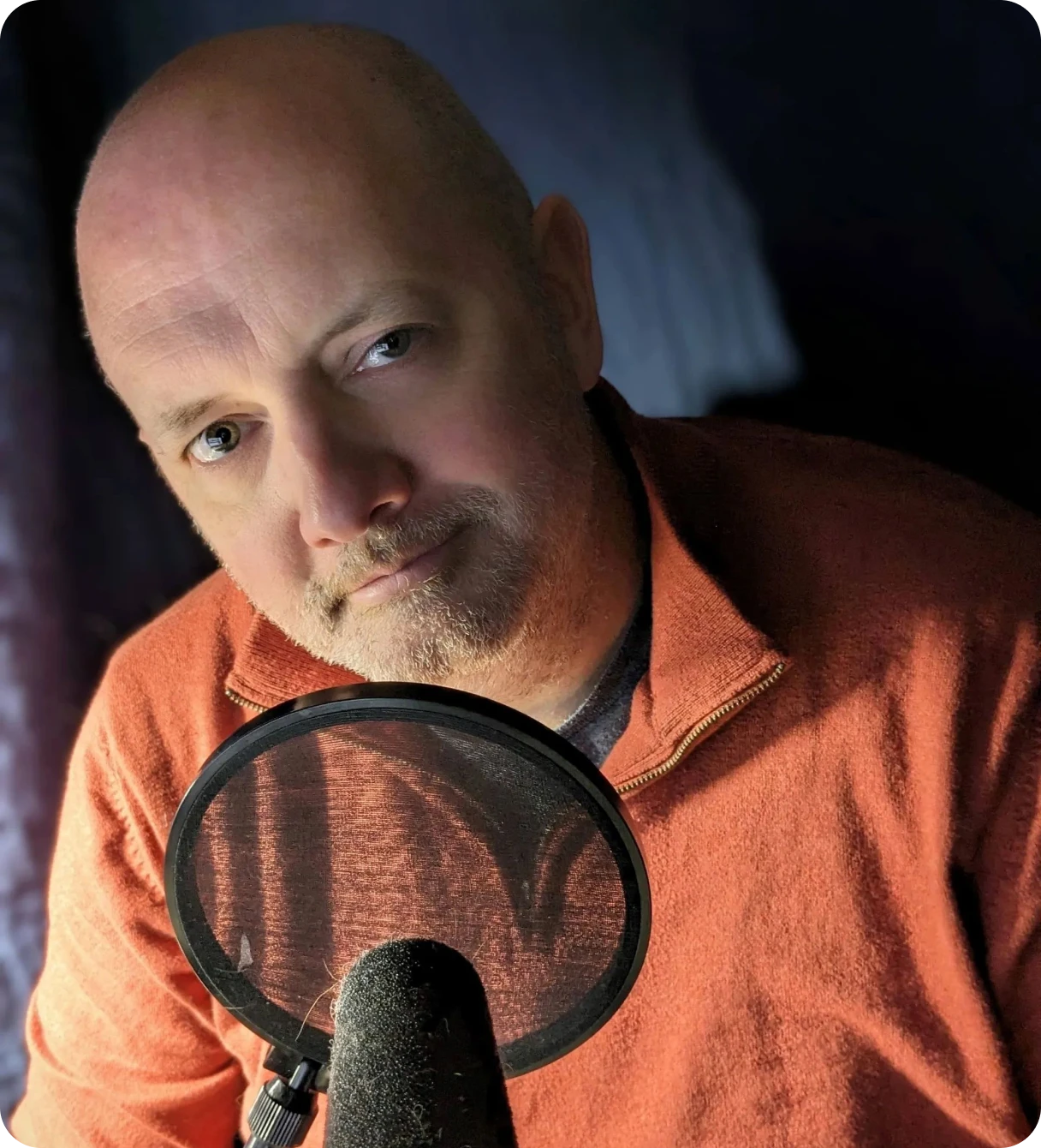 Man speaking into a microphone with a pop filter.